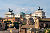 Statues of the WInged Victory atop the Victor Emmanuel II Monument in Rome, Italy. In front is the dome of the Church of Saints Luca and Martina.