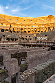 Interior of the Roman Colosseum or Flavian Amphitheater with golden sunset light in Rome, Italy. The tunnels under the floor of the arena were called hypogeum.