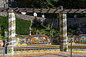 A colorful ceramic tile bench with a rustic scene & pillars at a ceramic shop on the Amalfi Coast of Italy.