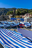 Boats with striped covers on the beach in off peak season at Monterosso al Mare, Cinque Terre, Italy.