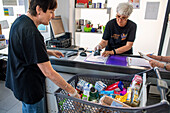 Poor and vulnerable families collecting donated products in the supermarket Rebost Solidari de Gracia, Gracia neighborhood, Barcelona, Spain, Europe. The Rebost Solidari de Gracia is a distributor entity of the Food Bank in its Sec, SERMA (fresh fruit and vegetables), cold chain (frozen and refrigerated products) and FEGA (products received from the EU) programs. An efficient management of all the food surpluses generated by the neighborhood (markets, supermarkets, shops, companies, restaurants, school canteens and others) is an important enough objective in itself, both for its use in the nei