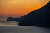 A colorful sunset sky behind the silhouette of the Sorrento Peninsula along the Amalfi Coast in Italy.