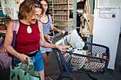 Poor and vulnerable families collecting donated products in the supermarket Rebost Solidari de Gracia, Gracia neighborhood, Barcelona, Spain, Europe. The Rebost Solidari de Gracia is a distributor entity of the Food Bank in its Sec, SERMA (fresh fruit and vegetables), cold chain (frozen and refrigerated products) and FEGA (products received from the EU) programs. An efficient management of all the food surpluses generated by the neighborhood (markets, supermarkets, shops, companies, restaurants, school canteens and others) is an important enough objective in itself, both for its use in the nei