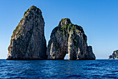 The Farallons or faraglioni, sea stacks off the coast of the island of Capri, Italy. L-R: Scopolo or Fuori & Mezzo, with a boat visible through its sea arch.