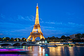 Scenic panorama of Eiffel Tower, Seine River, and pont d'lena in Paris, France; with a cruise passing by ferry