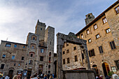 Die Ardinghelli-Türme und der Torre Grossa sowie die Piazza della Cisterna in der ummauerten Stadt San Gimignano, Italien. Die Spitze des Torre Rognosa ist rechts zu sehen.