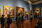 Visitors viewing Renaissance paintings in an exhibition hall in the Accademia Gallery in Florence, Italy.