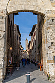 The Via San Giovanna passes through the Porta San Giovanni into the medieval city of San Gimignano, Italy. Behind is the Torre Grossa of the Palazzo Comunale.