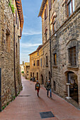 Touristen gehen die Via Palestro in der mittelalterlichen Stadt San Gimignano, Italien, hinauf.