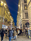 Pedestrians on the Via del Calzaiuoli at night in historic Florence, Italy.