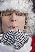 Frau bläst Schnee aus den Händen