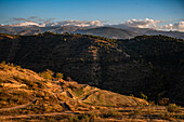 Sunset over the hills behind Granada and wide landscapes with the snowy Sierra Nevada behind, Granada, Andalusia, Spain