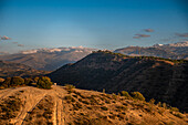 Sunset over the hills behind Granada and wide landscapes with the snowy Sierra Nevada behind, Granada, Andalusia, Spain