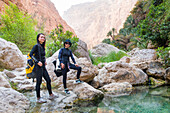 Two young women wearing canyoning gear in Wadi Shab, canyon near Tiwi, Sultanate of Oman, Arabian Peninsula