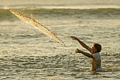 Man casting a weighted throw net at Nosara Boca (river mouth), local fishing spot, Boca Nosara, Nosara Beach, Guanacaste, Costa Rica