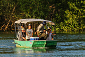 Tourists on boat trip through mangrove fringed Nosara River estuary and Biological Reserve at sunset, Boca Nosara, Nosara, Guanacaste, Costa Rica