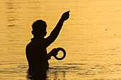 Local man handline fishing at the mangrove fringed Nosara Boca (river mouth) estuary at sunset, Nosara River, Boca Nosara, Guanacaste, Costa Rica