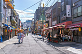 View of couple in traditional Kimono dress, shops and buildings in Asakusa, Taito City, Tokyo, Honshu, Japan