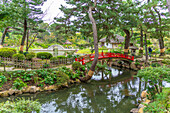 View of red footbridge over Takueichi Pond in Shukkeien Garden, Kaminoboricho, Naka Ward, Hiroshima, Honshu, Japan