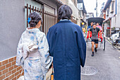 Blick auf ein Paar in Kimonos und Rikscha in Gion, Kyotoer Geisha-Viertel, Kyoto, Honshu, Japan