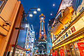 View of Tsutenkaku Tower and restaurants neon lights at dusk in the Shinsekai area, Osaka, Honshu, Japan