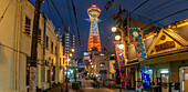 View of Tsutenkaku Tower and restaurants neon lights at dusk in the Shinsekai area, Osaka, Honshu, Japan