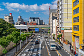 Blick auf eine belebte Straße und die Stadtsilhouette an einem sonnigen Tag im Shinsekai-Gebiet, Osaka, Honshu, Japan