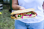 Char sausage hot dog with leaf salad and red cabbage