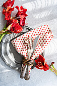 Silver cutlery and plates, amaryllis decoration and dotted cloth napkin