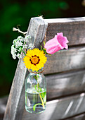 Kleiner Blumengruß in Mini-Glasvase am Gartenstuhl