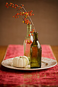 Autumnal still life with pumpkin and berry branches in bottles