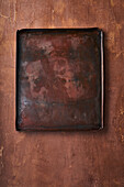 Empty baking tray on brown background next to napkin