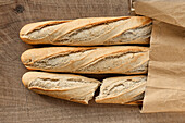 Three fresh baguettes in a paper bag