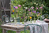 Gedeckter Tisch mit Blumenschmuck, Ringelblume (Calendula), Kosmee (Cosmos), Flammenblume (Phlox), Skabiose, Kugellauch (Allium) in Vasen