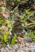 Steinmännchen und Farnblätter im sommerlichen Garten 