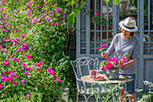 Frau mit Rosenstrauss, Rosenstauden (Rosa multiflora 'Taunusblümchen'), Kletterrose am Teehaus neben Sitzplatz