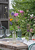 Gedeckter Tisch mit Blumenschmuck, Ringelblume (Calendula), Kosmee (Cosmos), Flammenblume (Phlox), Skabiose, Kugellauch (Allium) in Vasen