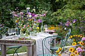 Gedeckter Tisch mit Blumenschmuck, Ringelblume (Calendula), Kosmee (Cosmos), Flammenblume (Phlox), Skabiose, Kugellauch (Allium) in Vasen