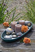 Steine mit Blattgold, Kerzen und Rosenblüten auf Tablett 
