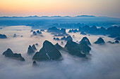 Luftaufnahme des in Nebel gehüllten Guilin-Gebirges mit ruhigen Karstformationen in der Morgendämmerung, Bezirk Yangshuo, China