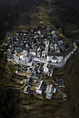 Aerial view of charming historic village with stone buildings and terraced rooftops,nestled in alpine mountain landscape,corippo,ticino,switzerland