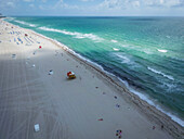 Aerial view of a beautiful sandy beach with lifeguard house and people relaxing on beach chairs,Miami Beach,Florida,United States
