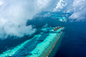 Panoramaluftaufnahme der Insel Huluwalu entlang des Barriereriffs bei tief hängenden Wolken, Malediven-Archipel