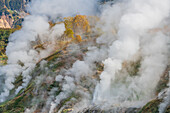 Luftaufnahme des majestätischen Tals der Geysire mit aufsteigendem Dampf in einer zerklüfteten Landschaft, Kamtschatka, Russland