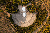 Aerial view of the ancient theater ruins surrounded by lush greenery and trees,Asklipiio,Greece