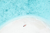Aerial Top Down View Of Female Model Lying On White Sand Beach In South Male Atoll,Maldives