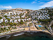 Aerial view of summer resort with buildings,beach,and swimming pool by the Aegean Sea,Sporkent,Bodrum,Turkey