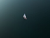 Luftaufnahme einer einsamen Yacht, die an einem bewölkten Sommernachmittag durch die Bucht segelt, Studland Bay, Dorset, England