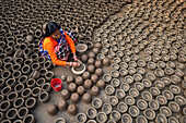 Bogura,Bangladesh - 27 January 2020: View of a woman colouring and painting clay pots in Bogura,Bangladesh
