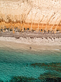 Aerial view of Balgowan beach with orange cliffs and turquoise water and two people casting a shadow on the beach,top down perspective,Yorke Peninsula,South Australia